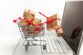 Paper boxes in a shopping cart on a laptop keyboard. Ideas about e-commerce, a transaction of buying or selling goods or Royalty Free Stock Photo