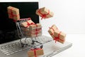 Paper boxes in a shopping cart on a laptop keyboard. Ideas about e-commerce, a transaction of buying or selling goods or Royalty Free Stock Photo