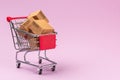 Paper boxes in shopping cart on Violet background with copy space. For online shopping business, promotion and marketing concept Royalty Free Stock Photo