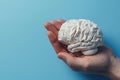 A paper brain in the palm of a person\'s hand. Working with human thinking