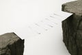 A paper bridge between two rocks, a symbol of connection and fragility. Space for text. Royalty Free Stock Photo