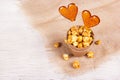 Paper bucket of caramel popcorn and two candies on a stick on a white wooden background. Lollipop in the shape of a heart Royalty Free Stock Photo
