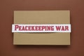 Paper card with phrase Peacekeeping War on brown background, top view