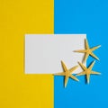 Paper card with three sea stars on blue and yellow paper background. Mock up, flat lay, copy space, top view. Summer vacation Royalty Free Stock Photo