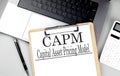 Paper clipboard with CAPM on laptop with pen and calculator Royalty Free Stock Photo