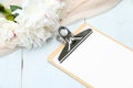 Paper clipboard mockup and peony flowers on blue wooden table. Flat lay, top view. Wedding planner, checklist, to do list concept Royalty Free Stock Photo