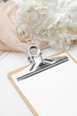 Paper clipboard mockup and peony flowers on white wooden table. Flat lay, top view. Wedding planner, checklist, to do list concept Royalty Free Stock Photo