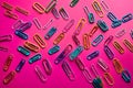 Paper clips of various colors on pink colored paper