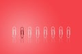 Red paper clip standing in row of group white paper clips. Royalty Free Stock Photo