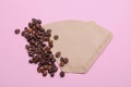 Paper coffee filter and beans on pale pink background, flat lay