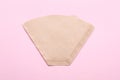 Paper coffee filter on pale pink background, top view