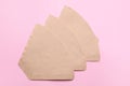 Paper coffee filters on pale pink background, flat lay