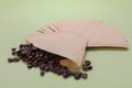 Paper coffee filters and scattered beans on pale olive background