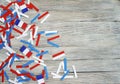 Paper confetti of the national colors of France, white-blue-red on a white wooden background with flags, concept Bastille day, Jul