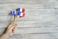 Paper confetti of the national colors of France, white-blue-red on a white wooden background with flags, concept Bastille day, Jul