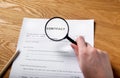 Paper contract on wood desk with magnifying glass in female hand Royalty Free Stock Photo