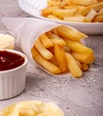 Paper conus of french fries chips potato and sauces on gry concrete background. copy space Royalty Free Stock Photo