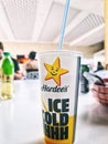 A paper cup branded Hardees stands on a table in the food court area