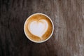 Paper cup of cappuccino coffee with beautiful latte art in the shape of heart on wooden background. Top view, copy space. Royalty Free Stock Photo