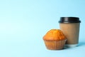 Paper cup and chocolate muffin on blue background space for text Royalty Free Stock Photo