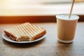 Paper cup of coffee and bitten sandwich on wooden background Royalty Free Stock Photo