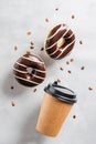 Paper cup with coffee drink or tea donut in chocolate coffee beans on a gray background. Creative fashionable levitation Royalty Free Stock Photo
