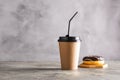 Paper cup with coffee drink or tea donut in chocolate icing on a gray background. Zero West food and drink concept. Royalty Free Stock Photo