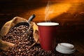 Paper cup of coffee with smoke and coffee beans on old wooden Royalty Free Stock Photo