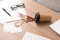 Paper cup with coffee spill on office desk Royalty Free Stock Photo