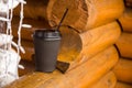 Paper cup with coffee stands on a wooden log