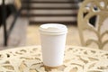 Paper cup of coffee on table outdoors, closeup. Takeaway drink