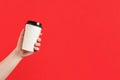 Paper cup of coffee or tea on a red background. Mockup of male hand holding paper cup isolated. Front view mockup of empty Royalty Free Stock Photo