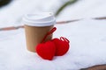 Paper cup for coffee to go and decorative red hearts on the snow in winter. Concept of serious relationship and valentine`s day Royalty Free Stock Photo