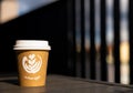 A paper cup of coffee with a white lid stands on a table in the sun Royalty Free Stock Photo