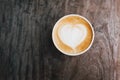 Paper cup of fresh delicious cappuccino coffee with beautiful latte art on wooden background. Royalty Free Stock Photo