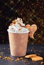 Paper cup with hot drink with whipped cream on dark background. Recycling and eco friendly concept.