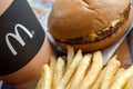 Minsk, Belarus, February 18, 2018: Paper cup with a logo, cheeseburger and french fries at McDonald`s restaurant