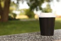 Paper cup on parapet in park, space for text. Coffee to go Royalty Free Stock Photo