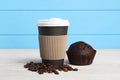 Paper cup with plastic lid, coffee beans and muffin on white wooden table. Coffee to go Royalty Free Stock Photo