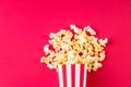 Paper cup with popcorn on color background. Striped box with popcorn on red background.Popcorn in red and white striped cardboard Royalty Free Stock Photo