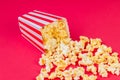 Paper cup with popcorn on color background. Striped box with popcorn on red background.Popcorn in red and white striped cardboard Royalty Free Stock Photo