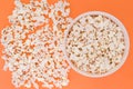 Paper cup with popcorn, and popcorn scattered on a orange background, top view, copyspace Royalty Free Stock Photo