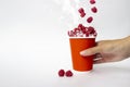 Paper cup of Raspberries in hand on white background. Fresh raspberry smoothie splash, close up Royalty Free Stock Photo