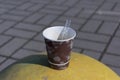 Paper cup with takeaway coffee stands on a concrete protective hemisphere on the street