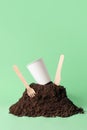 Paper cup and wooden fork, knife in heap of soil on green, vertical with copy space. Compostable or biodegradable Royalty Free Stock Photo