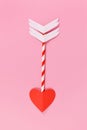 Paper cupid love arrow with heart shaped tip on pink background