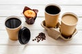 Paper cups with black coffee and cappuccino to take away, beans, muffin on white wooden background Royalty Free Stock Photo