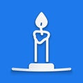 Paper cut Burning candle in candlestick icon isolated on blue background. Cylindrical candle stick with burning flame Royalty Free Stock Photo