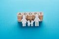 Paper cut family holding hands on blue background with adopt lettering on wooden cubes.