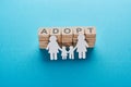 Paper cut lesbian family holding hands on blue background with adopt lettering on wooden cubes.